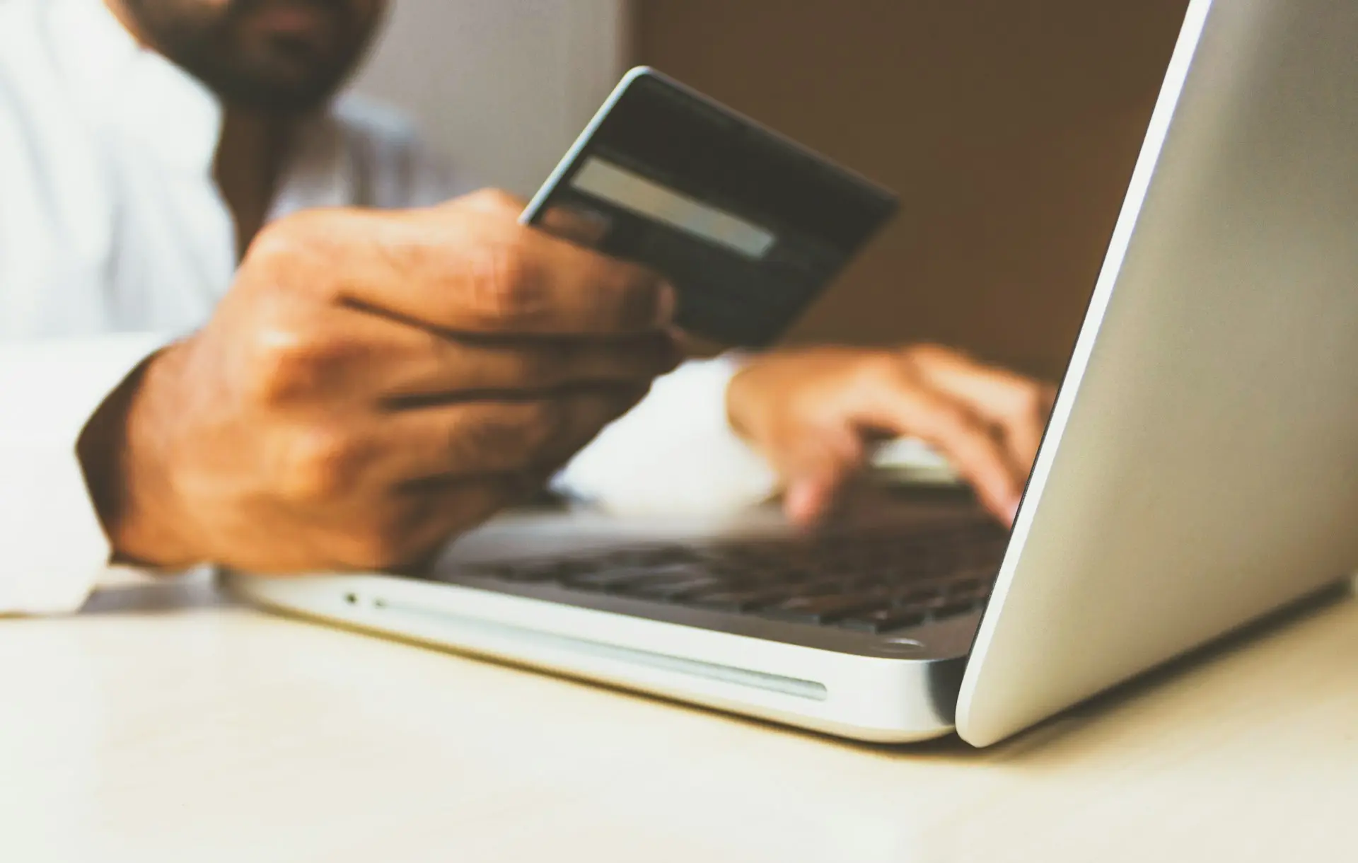 person using laptop computer holding card