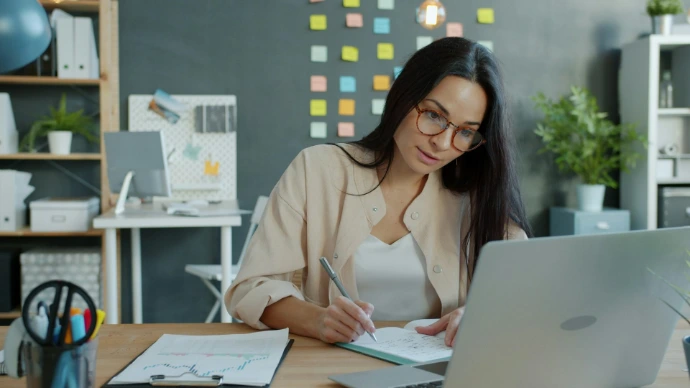 Mujer trabajando en un escritorio con laptop y cuaderno
